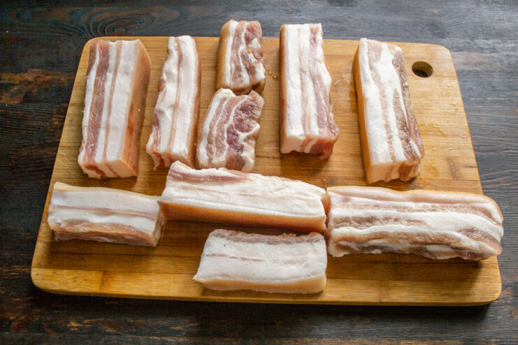 Trozos de tocino curado listos sobre una tabla de cortar de madera