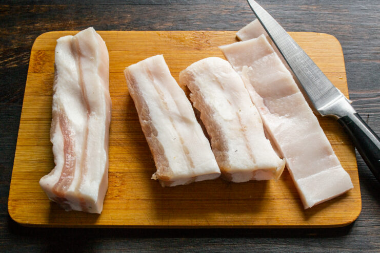 Cortar la piel dura de la panceta curada usando un cuchillo bien afilado