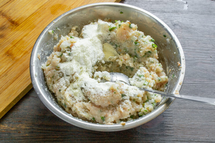 Añadiendo leche en polvo Cucharada de leche en polvo sobre la masa de pollo picado