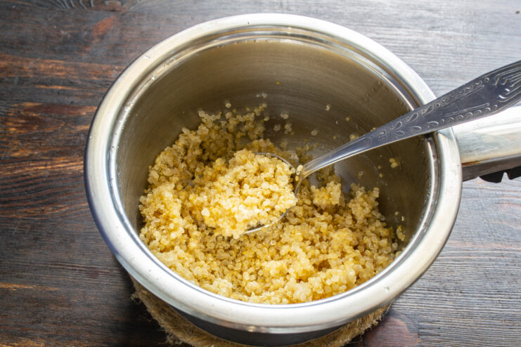 Granos de quinoa cocida reposando en un cazo de metal.