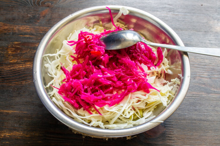 Col fresca mezclada con col fermentada de un tono rosa vibrante.