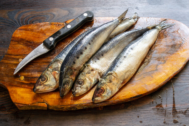 Selección del pescado para el marinado Arenque ivasi fresco sobre una tabla de cortar de madera