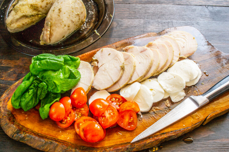 Hojas frescas de albahaca verde junto a los demás ingredientes cortados de la ensalada