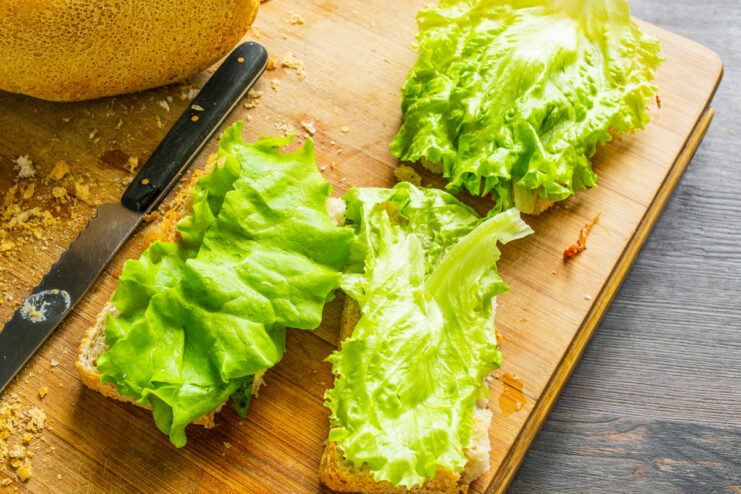Hojas de lechuga fresca y crujiente dispuestas sobre el pan untado.