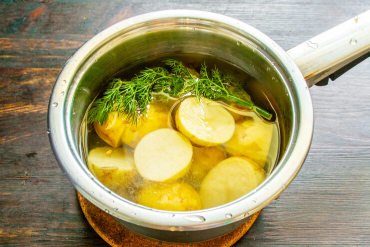 Patatas cociéndose en una olla con eneldo fresco