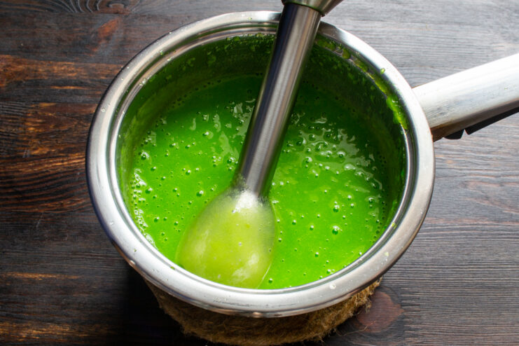 Batido de la masa Batiendo la masa verde con una batidora de mano.