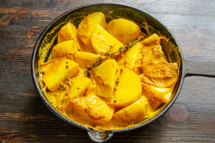Patatas tiernas y doradas con salsa en una sartén de hierro fundido